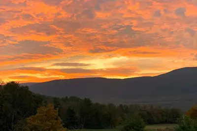 a sunset in the mountains with trees in the foreground at Manchester Center Home with Green Mtn Views! in Manchester Center