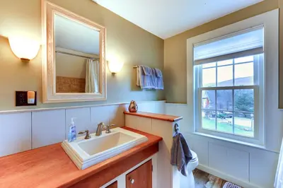 a bathroom with a sink and a mirror and a window at Manchester Center Home with Green Mtn Views! in Manchester Center