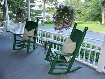 two green rocking chairs sitting on a porch with flowers at Anne's Washington Inn in Saratoga Springs