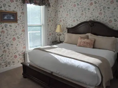 a bedroom with a large bed with floral wallpaper at Anne's Washington Inn in Saratoga Springs