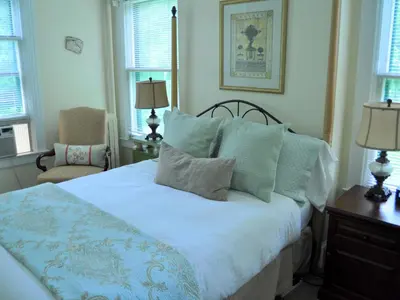 a bedroom with a bed and a chair and windows at Anne's Washington Inn in Saratoga Springs