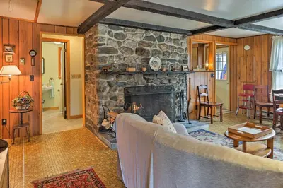 a living room with a large stone fireplace at East Otis Reservoir Cabin with Porch - Walk to Lake! in East Otis