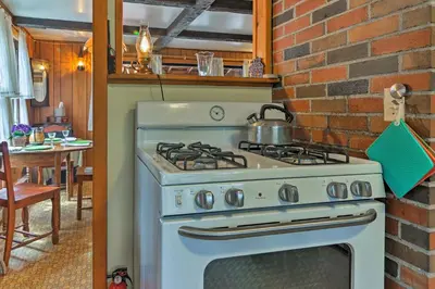 a white stove in a kitchen with a brick wall at East Otis Reservoir Cabin with Porch - Walk to Lake! in East Otis