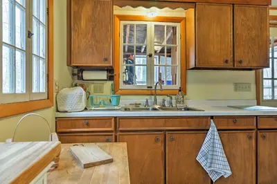 a kitchen with wooden cabinets and a sink at East Otis Reservoir Cabin with Porch - Walk to Lake! in East Otis