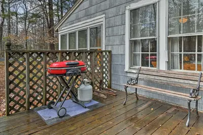 a grill on a deck with a bench and a house at East Otis Reservoir Cabin with Porch - Walk to Lake! in East Otis