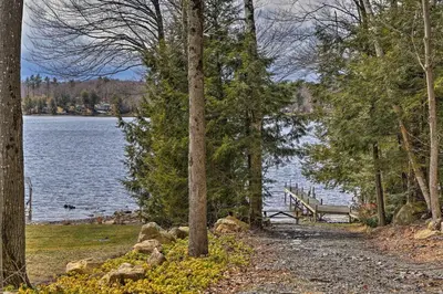 a bench on a path next to a lake at East Otis Reservoir Cabin with Porch - Walk to Lake! in East Otis