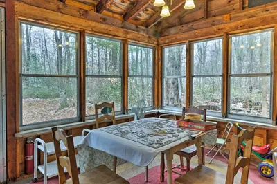 a dining room with a table and chairs and windows at East Otis Reservoir Cabin with Porch - Walk to Lake! in East Otis