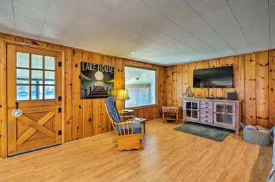 a living room with wood paneling and a sliding barn door at Picturesque Cottage with Sunroom on Ashmere Lake! in Hinsdale