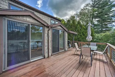 a wooden deck with a table and chairs on it at Picturesque Cottage with Sunroom on Ashmere Lake! in Hinsdale
