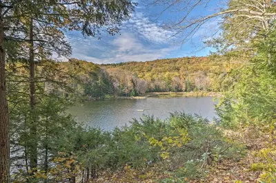 a lake in the middle of a forest at Lakefront Berkshires Retreat with Deck, Dock and Boat! in Great Barrington
