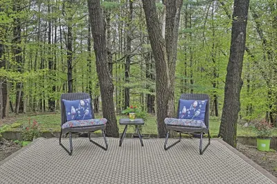 two chairs sitting on a patio in the woods at Beautiful Lenox Home, 3 Mi to Shakespeare and Co! in Lenox