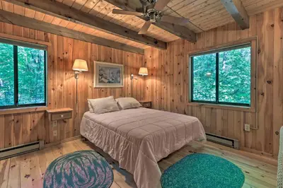 a bedroom with a bed in a room with wooden walls at Cabin with 3 Acres, Tennis Courts By 4 Ski Mtns in Sandisfield