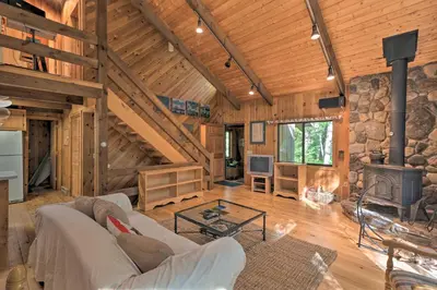 a living room with a fireplace and a stone wall at Cabin with 3 Acres, Tennis Courts By 4 Ski Mtns in Sandisfield