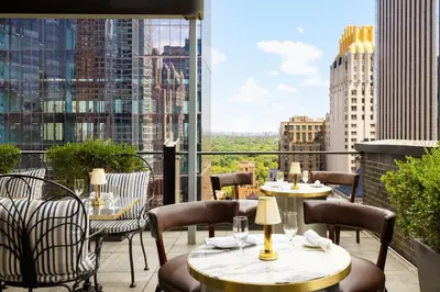 a balcony with tables and chairs and a view of a city at Le Meridien New York, Central Park in New York