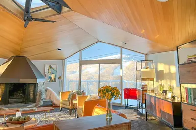 a living room with a fireplace and a large window at Pristine West Dover Home with Deck and Mountain Views! in West Dover
