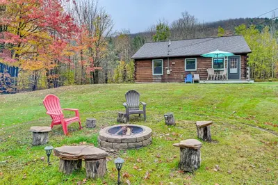 two chairs and a fire pit in front of a log cabin at High Peak Heaven Cozy Log Cabin on 1 Acre! in Windham