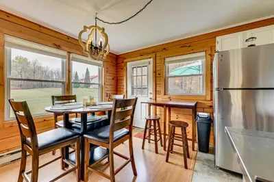 a kitchen with a table and chairs and a refrigerator at High Peak Heaven Cozy Log Cabin on 1 Acre! in Windham