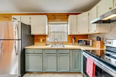 a kitchen with green cabinets and a stainless steel refrigerator at High Peak Heaven Cozy Log Cabin on 1 Acre! in Windham