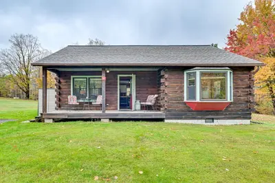 a small log cabin with two chairs in a yard at High Peak Heaven Cozy Log Cabin on 1 Acre! in Windham
