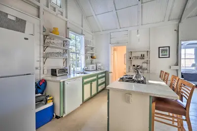 a kitchen with green cabinets and a white refrigerator at Cozy Stockbridge Cabin - Walk to Beach and Lake! in Stockbridge