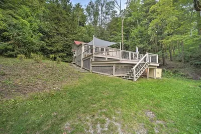 a large house with a porch on a grass field at Cozy Stockbridge Cabin - Walk to Beach and Lake! in Stockbridge