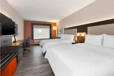 a hotel room with two beds and a flat screen tv at Holiday Inn Express & Suites Jersey City - Holland Tunnel by IHG in Jersey City