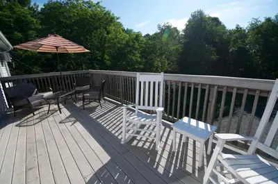 a deck with chairs and an umbrella and a table at East Shore Lodging in Hawley