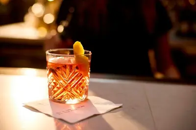 a drink on a table with a lemon in it at Archer Hotel New York in New York