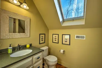 a bathroom with a sink and a toilet and a window at Luxe Green Barn Near Skiing with Mt Equinox Views! in Manchester Center