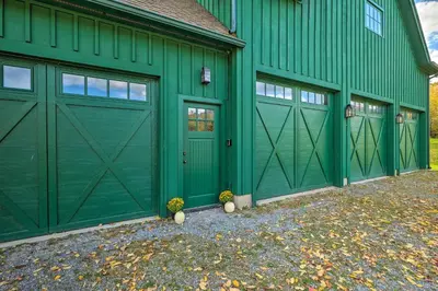 a green barn with two garage doors on it at Luxe Green Barn Near Skiing with Mt Equinox Views! in Manchester Center
