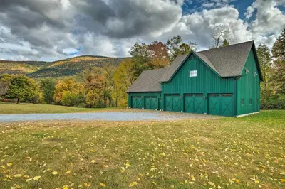 a green barn in the middle of a field at Luxe Green Barn Near Skiing with Mt Equinox Views! in Manchester Center