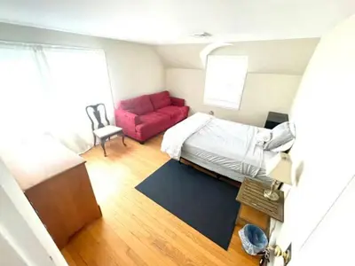 a small bedroom with a bed and a red couch at Town Plot Waterbury in Waterbury