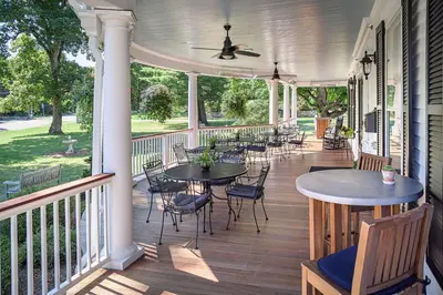 a screened porch with tables and chairs and a ceiling fan at The West Lane Inn in Ridgefield