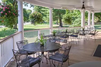 a covered porch with tables and chairs and flowers at The West Lane Inn in Ridgefield