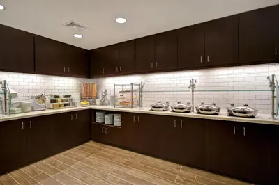 a kitchen with dark brown cabinets and white tiles at Residence Inn Middletown Goshen in Middletown