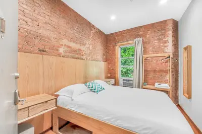 a bedroom with a bed and a brick wall at Morris Guest House in Bronx
