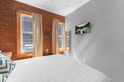 a bedroom with a white bed and two windows at Morris Guest House in Bronx