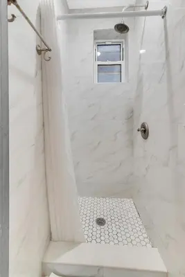 a white bathroom with a shower with a window at Morris Guest House in Bronx