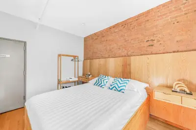 a bedroom with a large bed with a brick wall at Morris Guest House in Bronx