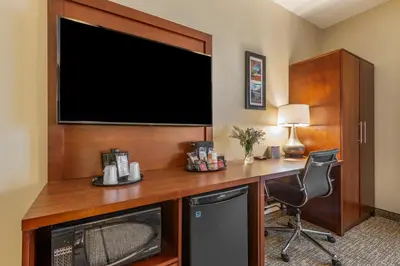 a hotel room with a desk with a large television at Comfort Inn Brewster in Brewster