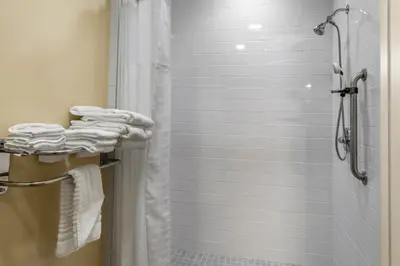 a bathroom with a shower with white towels at Comfort Inn Brewster in Brewster