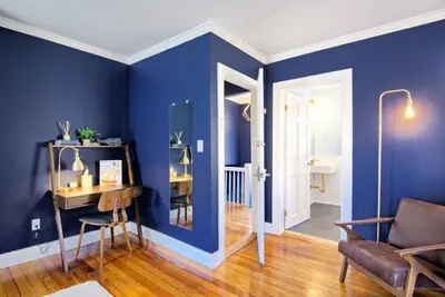 a living room with blue walls and a chair and a desk at Nautical Nest Hudson in Hudson