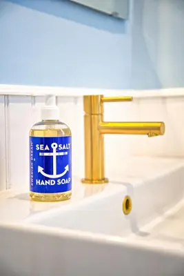 a bottle of hand soap sitting on a bathroom sink at Nautical Nest Hudson in Hudson