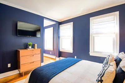 a bedroom with blue walls and a bed and a dresser at Nautical Nest Hudson in Hudson