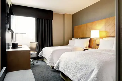 a hotel room with two beds and a desk at Hampton Inn Brooklyn Downtown in Brooklyn