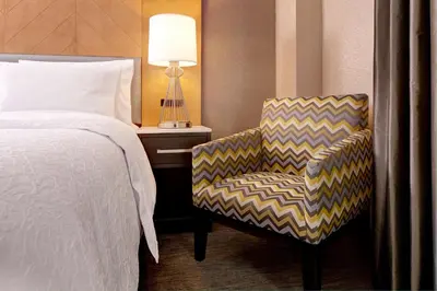 a bedroom with a bed and a chair and a lamp at Hampton Inn Brooklyn Downtown in Brooklyn