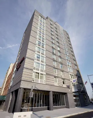 a tall building with a flag in front of it at Hampton Inn Brooklyn Downtown in Brooklyn