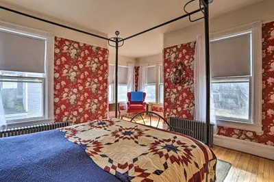 a bedroom with a bed and windows and a chair at Historic House with Record Player, Walk to Downtown! in Roxbury