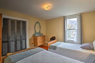 a bedroom with two beds and a dresser and a mirror at Historic House with Record Player, Walk to Downtown! in Roxbury