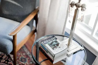 a glass table with two books and a lamp on it at Granville House in Great Barrington